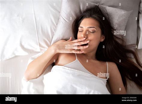 Pretty Girl Yawning On Her Warm Bed As She Gently Awakes Stock Photo