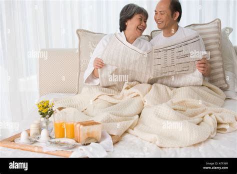 Mature Couple Sitting On The Bed Smiling Stock Photo Alamy