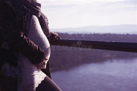 Pregnant Woman Standing Up On A Hill Looking Across The River Stock