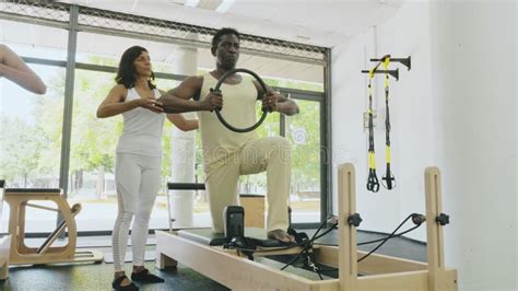 Hombre Haciendo Ejercicio En El Reformador De Pilates Con Entrenadora