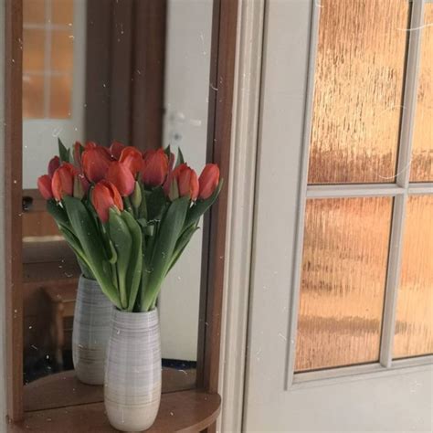 A Vase Filled With Red Tulips Sitting On Top Of A Wooden Table Next To