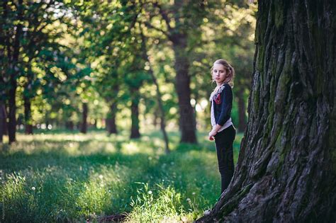 Girl Standing Beside A Large Tree In A Park By Stocksy Contributor