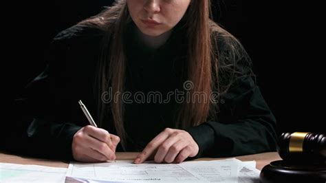 Female Sitting At The Desk With Wooden Hammer And Paper Documents Dark