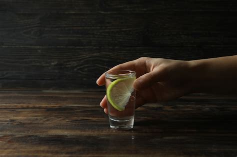 Premium Photo Female Hand Hold Shot Of Vodka Or Tequila With Lime