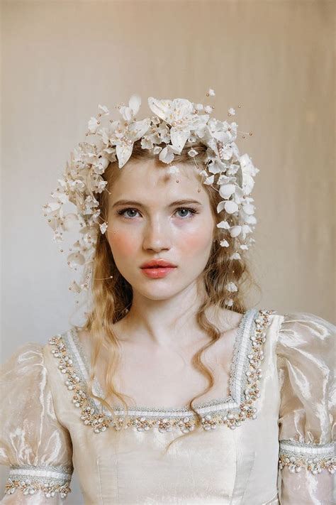 A Woman Wearing A White Dress With Flowers On Her Head And Hair In Braids