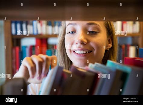 Young Girl Standing In Traditional Old Library At Bookshelves Looking