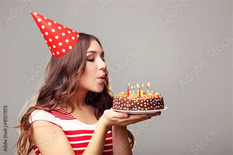 Young woman blowing out candles on birthday cake Stock Photo | Adobe Stock