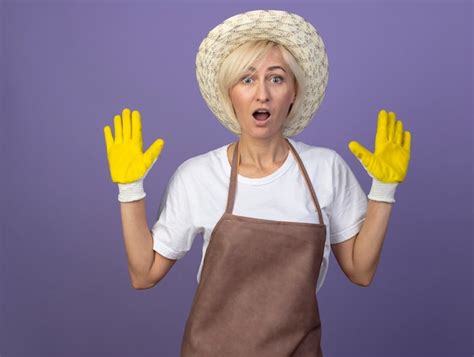 Femme Jardinière Blonde D âge Moyen Impressionnée En Uniforme Portant Un Chapeau Et Des Gants De