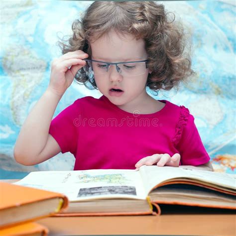 Petite Fille Intelligente Avec Des Glaces Affichant Un Livre Photo