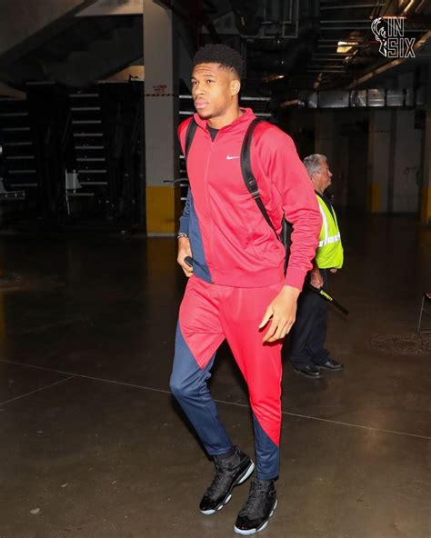 A Man In Red And Blue Tracksuits Is Walking Through An Indoor Space