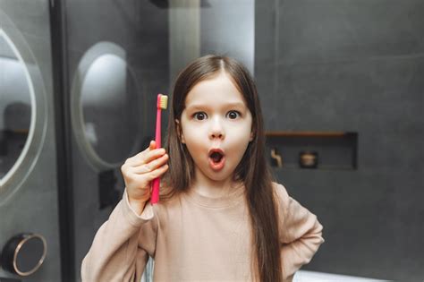 Heureuse Petite Fille Se Brosser Les Dents Devant Un Miroir De Salle De