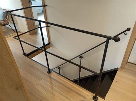 An Open Stair Rail In The Corner Of A Room With Wood Floors And White Walls