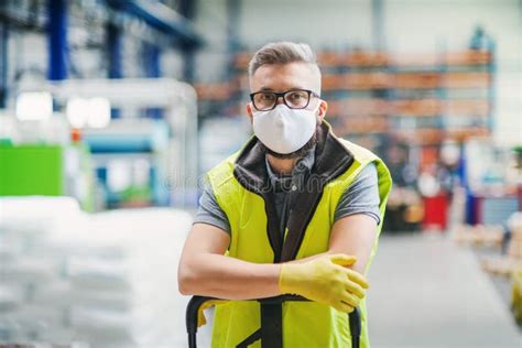 Man Worker With Protective Mask Standing In Industrial Factory Or