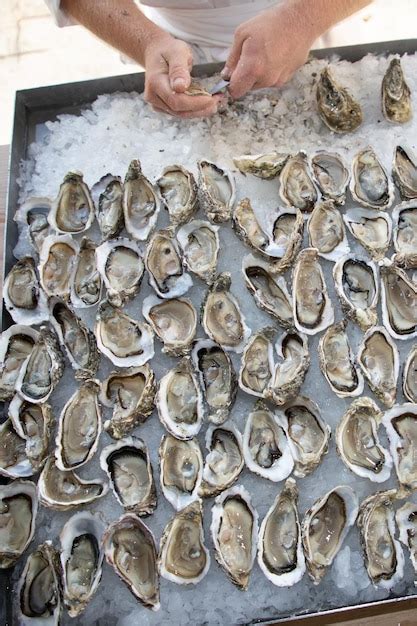 Premium Photo | Man opens fresh oysters in french restaurant in ...