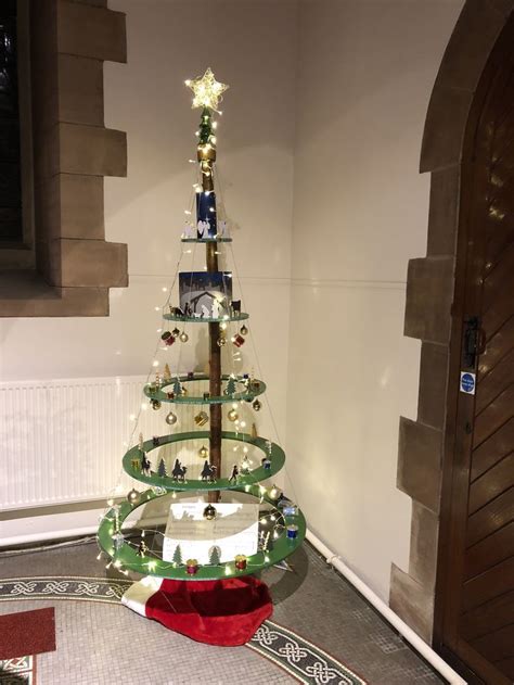 A Small Christmas Tree Is On Display In The Corner Of A Room With A Door