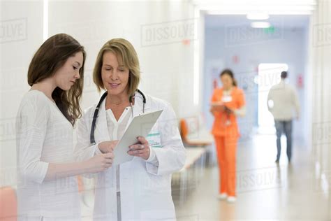 Doctor And Patient Reviewing Medical Record In Hospital Corridor