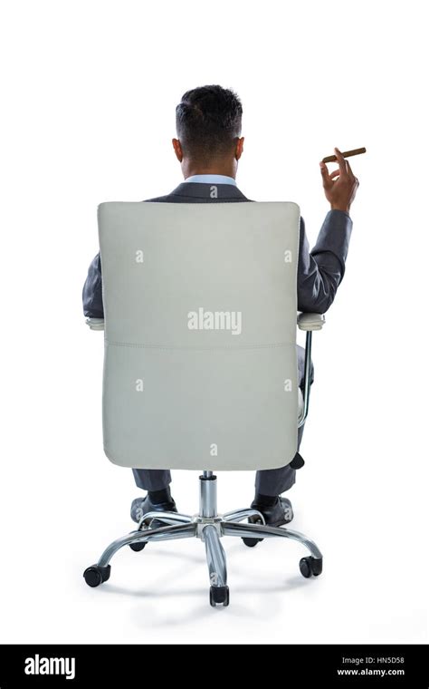 Rear View Of Businessman Holding Cigar Against White Background Stock