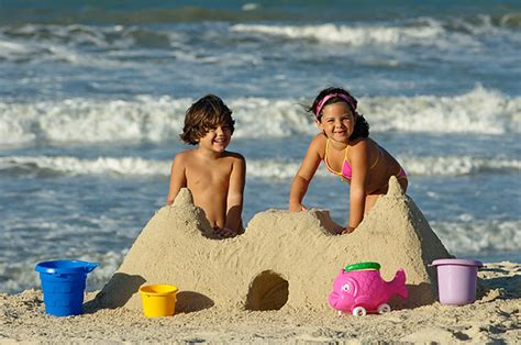 Crianças brincando na praia de castelo de areia Just Real Moms Blog