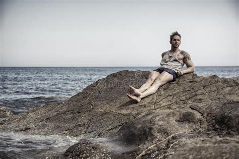 Homem Muscular Consider Vel Na Praia Que Senta Se Em Rochas Foto De