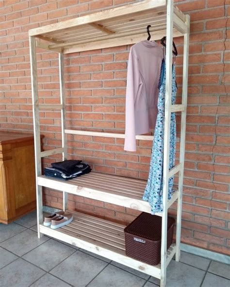 A Coat Rack With Clothes Hanging On It Next To A Brick Wall And Wooden