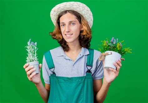 Hombre Joven Jardinero Vestido Con Mono Y Sombrero Sosteniendo Plantas