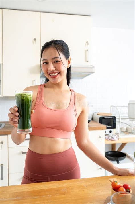 A Beautiful Asian Woman In Sportswear Is Showing Her Glass Of Healthy