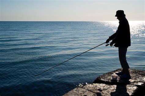 La Silueta De Un Pescador Atrapa Peces En El Mar Foto Premium