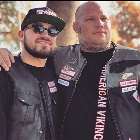 Two Men Standing Next To Each Other Wearing Leather Jackets And Patches