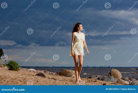 Beautiful Slim Barefoot Girl Walking On A Beach Against The Sea Stock