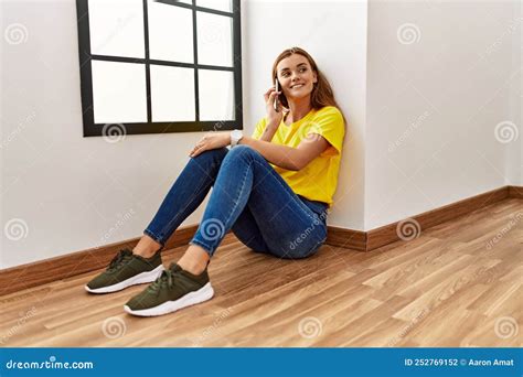 Young Woman Talking On The Smartphone Sitting On Floor At Empty Room