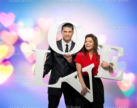 Beautiful Smiling Couple Holding Word Love Over Bokeh Background