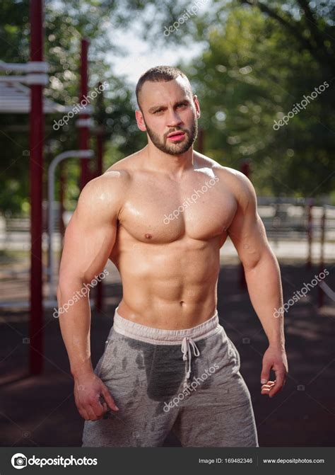 Sexy And Muscular Shirtless Bodybuilder Man Showing Off On A Blurred Background Working Out