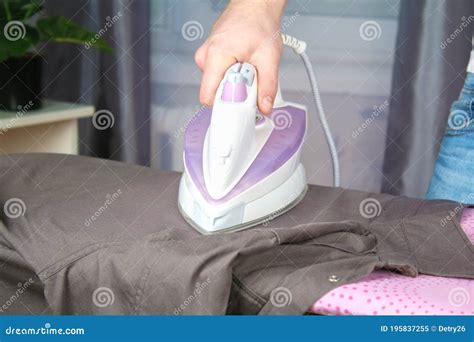 A Man Strokes Linen With An Electric Iron On An Ironing Board