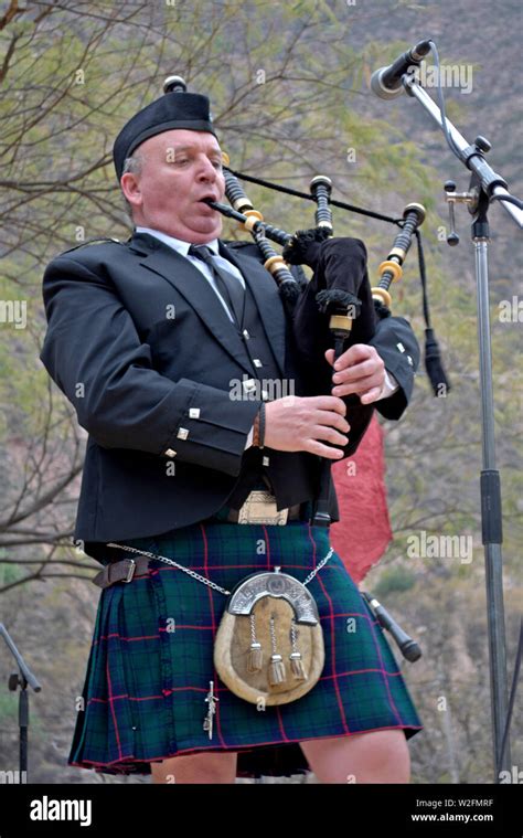 A Man Wearing A Scottish Kilt Playing The Bagpipes At A Festival Stock