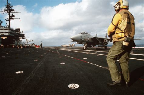 A Flight Deck Crew Member Stands By As An F A Tomcat Aircraft Taxis