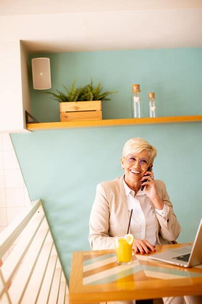 Mulher S Nior Usando Telefone Celular Enquanto Trabalhava No Laptop E