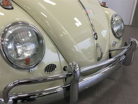 The Front End Of An Old Vw Bug In A Showroom With Chrome Trim