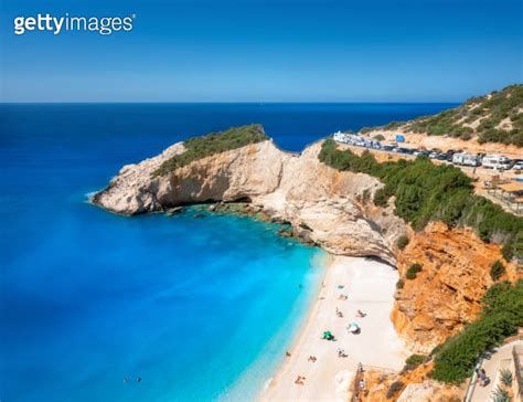 Aerial View Of Blue Sea Rock Sandy Beach With Umbrellas At Sunny Day