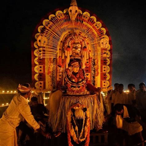 A Man Standing Next To An Elaborately Decorated Statue