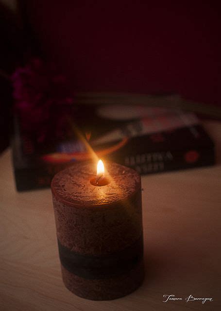 A Lit Candle Sitting On Top Of A Wooden Table Next To A Stack Of Books