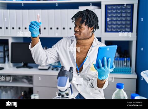 African American Man Scientist Using Touchpad Holding Test Tube At