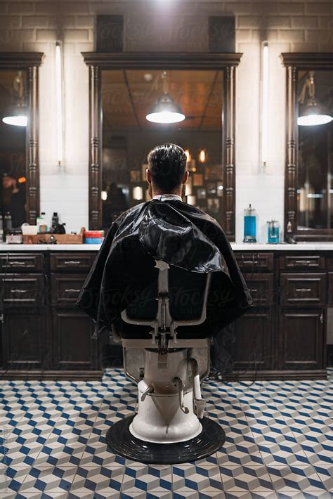 Back View Of Customer Sitting On Leather Chair In Barber Shop By