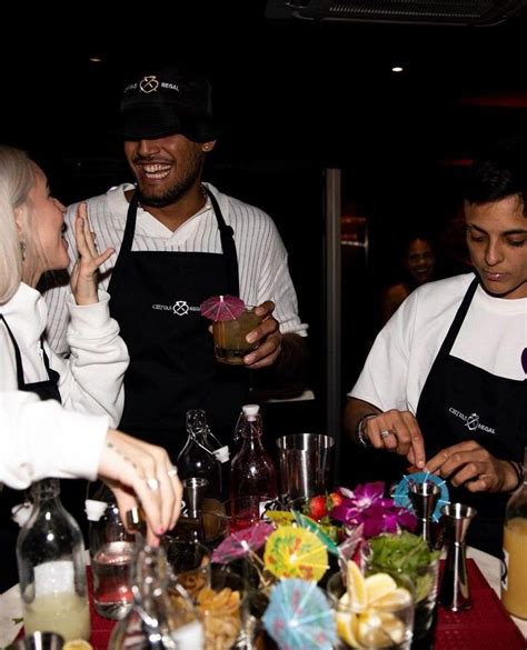 A Group Of People Standing Around A Table With Food And Drinks In Front