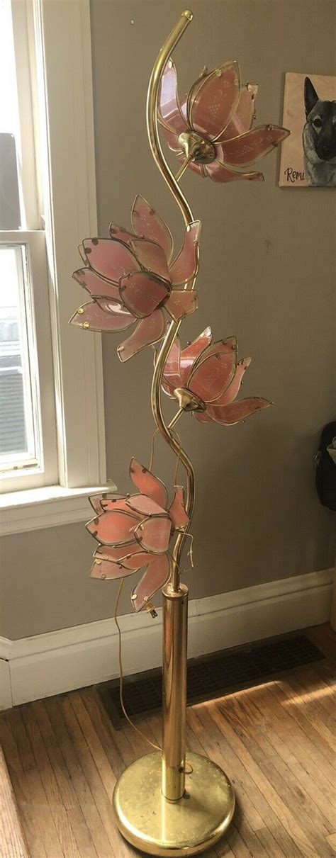 A Metal Sculpture With Pink Flowers Sitting On Top Of A Wooden Floor