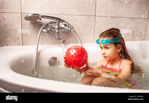 Sourire petite fille drôle dans un maillot de bain aime jouer le ballon