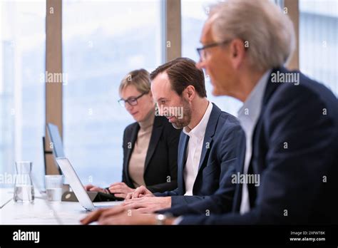 Mature Businessman Using Laptop While Working With Colleagues In Office