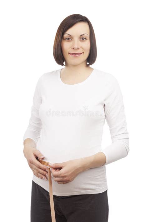 One Pregnant Brunette Woman Posing With Measurement Tape In White Shirt While Taking Dimensions