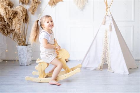 Une Petite Fille Se Balance Sur Un Cheval Bascule En Bois La Maison