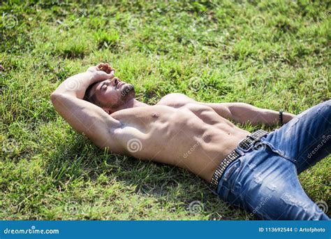 Shirtless Fit Male Model Relaxing Lying On The Grass Stock Photo