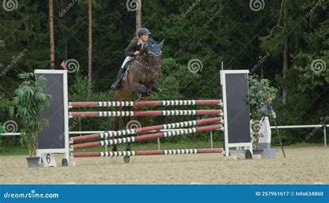 Female Jockey Riding Her Brown Thoroughbred Horse And Jumping Over